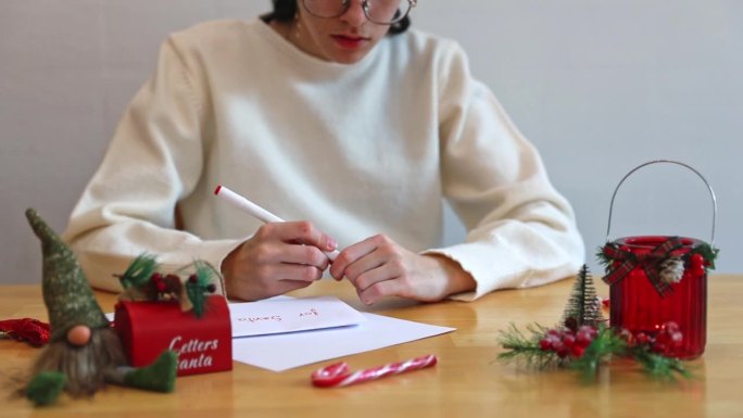 一个十几岁的女孩在餐桌上给圣诞老人的信上签了字。