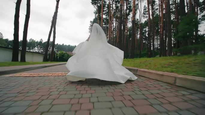 新娘穿着白色的礼服在公园里奔跑。在一个不幸的婚礼上，新娘从婚礼上逃跑了