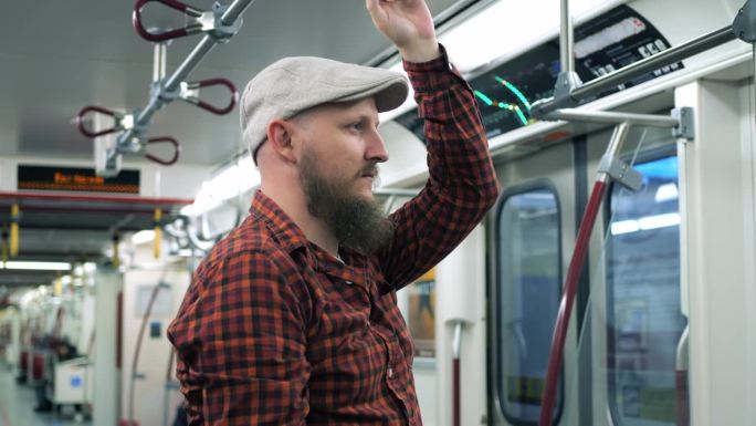 疲惫的睡眠不足的千禧一代乘地铁去市中心疲惫的戴着帽子的大胡子去上班努力工作挣钱的特写追求金钱的概念，