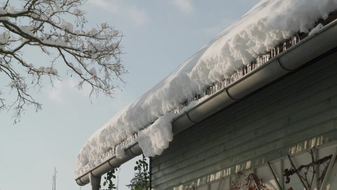 阴沟里的冰柱和被雪覆盖的屋顶