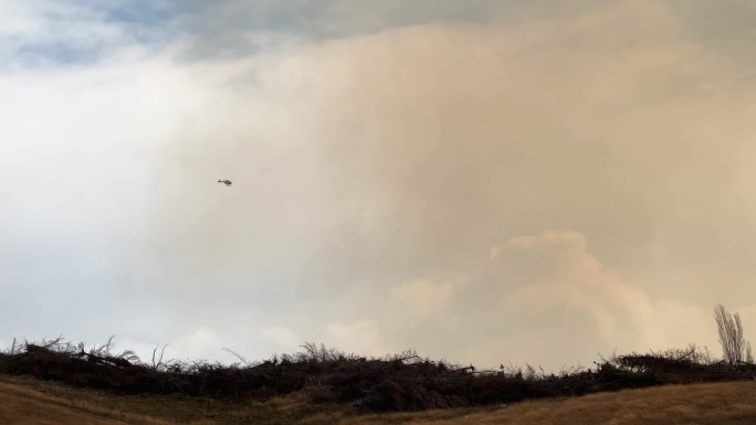 2023年，新西兰特威泽尔，直升机飞向浓浓的棕色野火烟雾;平移跟踪镜头