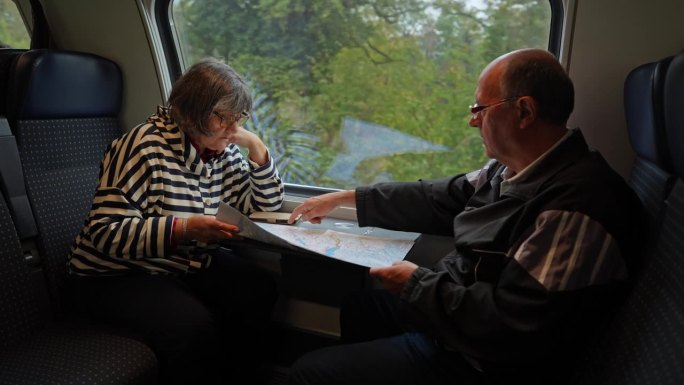 一对老年游客夫妇在火车上阅读城市地图