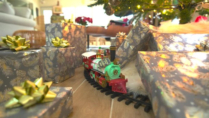 “迷人的库存镜头:在节日圣诞树下滑翔，礼物丰富，展示模型火车，在一个令人愉快的反向滑动镜头中传播快乐