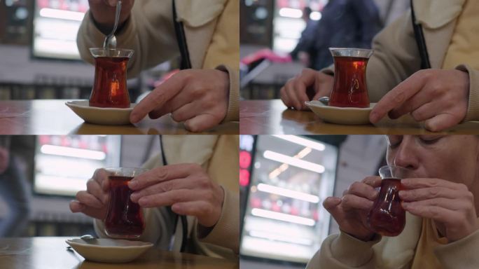 一名妇女在街边的咖啡馆里喝着国家杯的红茶。女性用手用茶匙搅拌热饮。