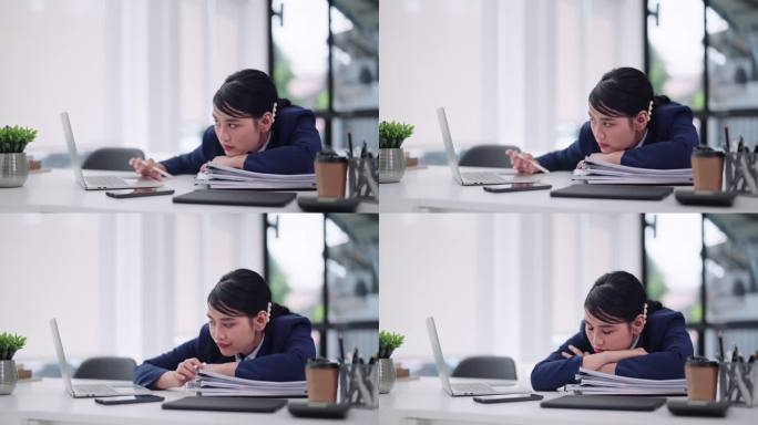 一名亚洲女商人坐在办公桌前对着笔记本电脑工作，感到无聊和困倦，最终进入小睡状态。捕捉办公室远程工作生
