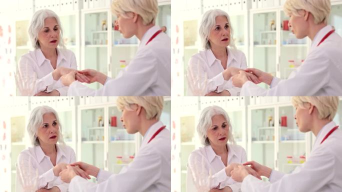风湿病医生在诊所4k慢动作电影中检查老年妇女患者的手部关节