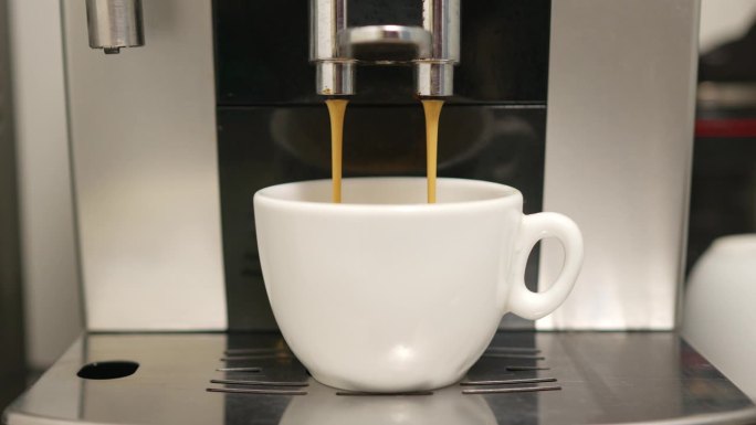 一只手把一个白色咖啡杯放进浓缩咖啡机