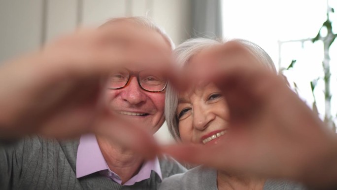 爱心心形平安。老年夫妇用手做心形。成年、成熟、年老的丈夫、妻子表现出心脏征兆。快乐的退休家庭。我爱你