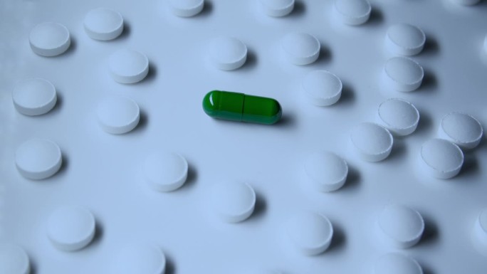 绿色胶囊周围环绕着其他传统的白色药片、医疗处方、有活性物质和没有活性物质的药物