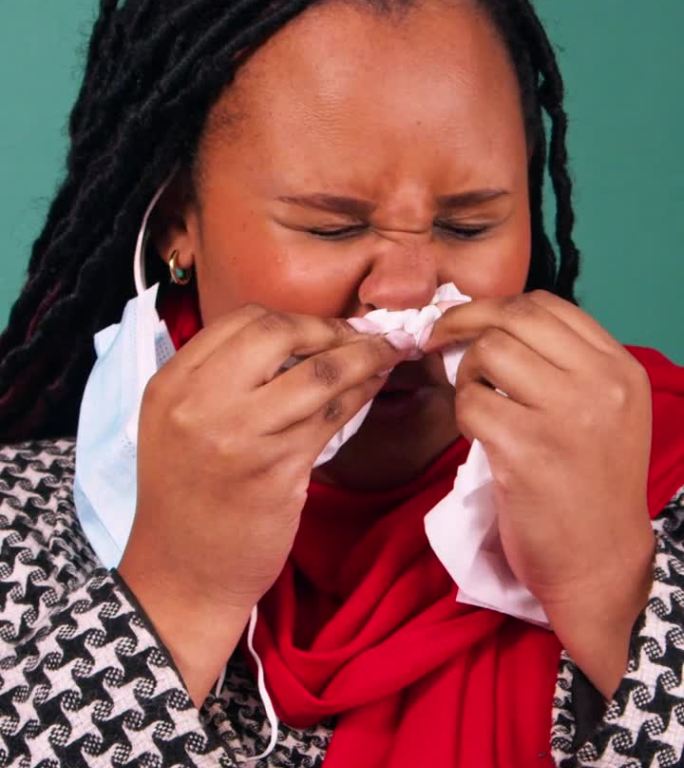 一个生病的黑人妇女的画像，她擤着鼻子，戴着外科口罩