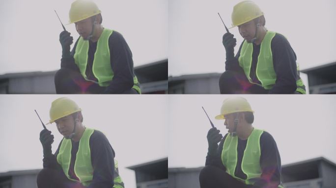 太阳能发电厂的亚洲中间人工程师穿着防护服，戴着头盔，通过无线电与团队沟通。