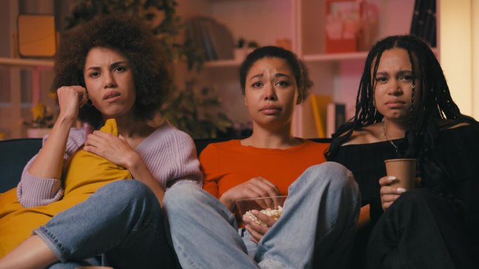 三个情绪化的非裔美国妇女在看电视情节剧时哭泣