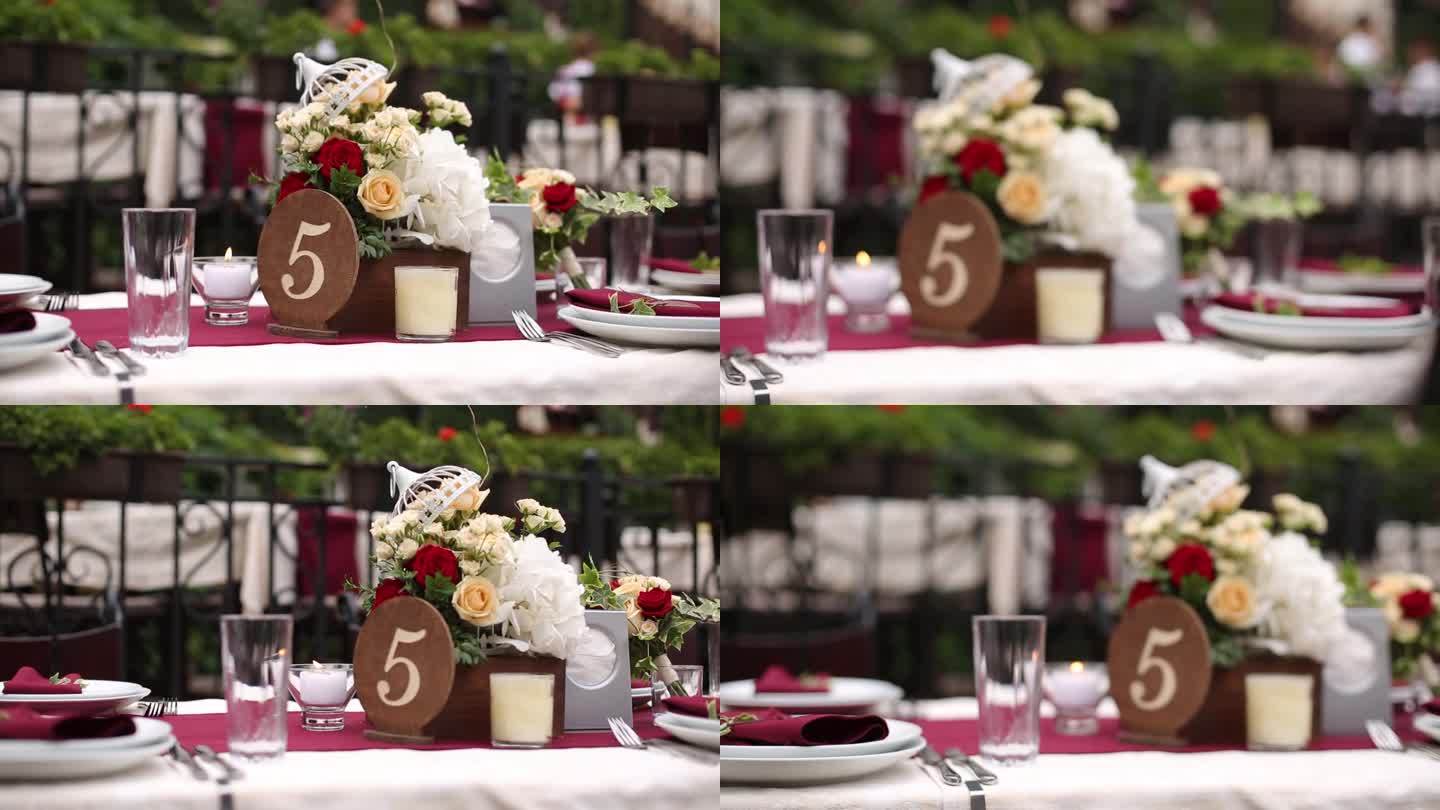 优雅的户外婚礼台面与花卉安排。红白颜色的主题，编号的中心，餐桌设置庆祝活动。理想的镜头浪漫的场合，活