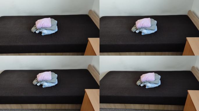 学生宿舍里的一张床已经整理好，一叠干净的床单已经准备好要换了。换床单