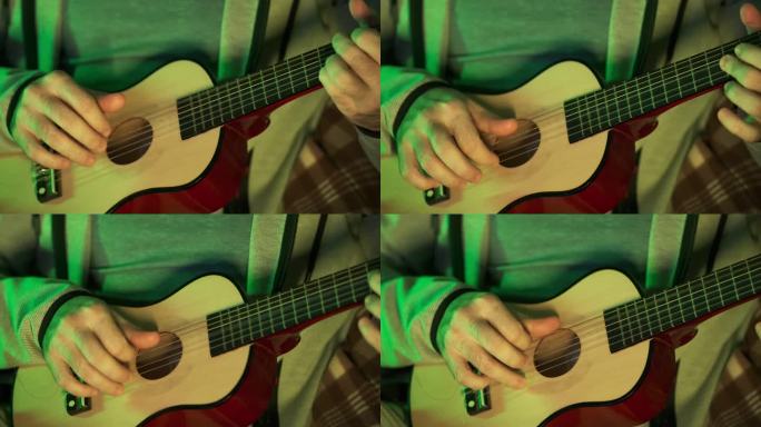 一个人手里拿着一把小尤克里里吉他，学着弹它。特写，绿色大气光