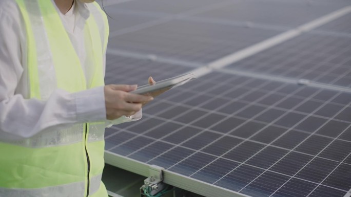 在太阳能发电站现场工作的维护工程师手持数码平板电脑。