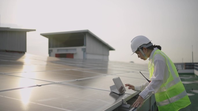 在太阳能发电站现场工作的维护工程师手持数码平板电脑。