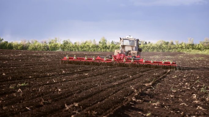 在一个阳光明媚的夏日里，红色联合收割机正在田地里犁地，准备种新小麦。大片农田。技术工程用农业设备。生