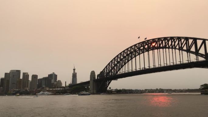 日落时分的悉尼海港大桥，篝火的烟雾缭绕。