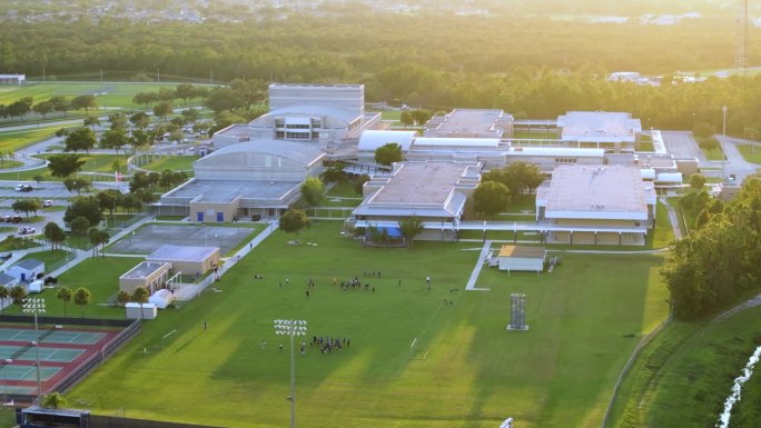 日落时分，美国公立学校的孩子们在校园里的体育馆里玩美式足球。美国的体育锻炼教育