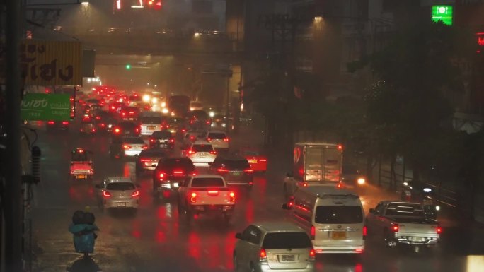 在一个雨夜，许多汽车在城市道路上堵塞。红色的背光反射在潮湿的沥青上
