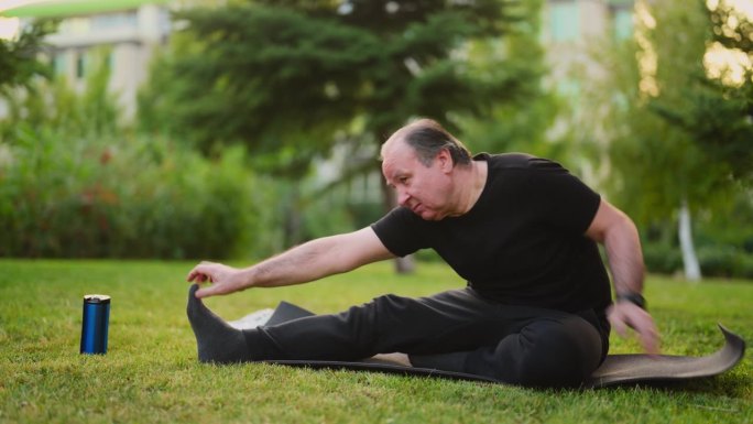 老人在公园上瑜伽课，在瑜伽垫上伸展身体