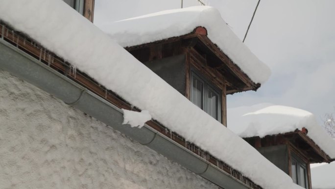 阴沟里的冰柱和被雪覆盖的屋顶