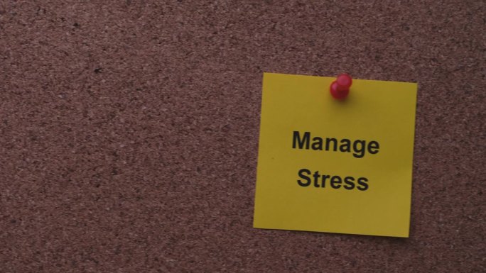一张写着“控制压力”的黄色纸条别在一块软木板上。