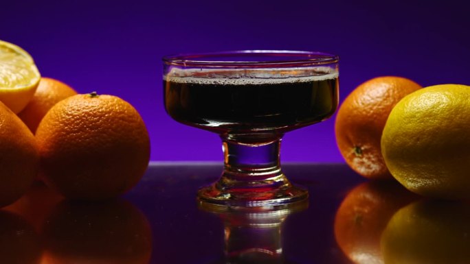美丽的照明背景。股票剪辑。漂亮宽敞的杯子里放着酒精饮料，背景是橘子和橘子。高品质4k画面