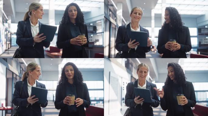 优雅而有能力的女商人走在明亮的办公大楼里，她们用智能手机讨论业务。聪明自信的人会在去开会的路上分享项