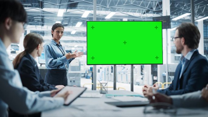 电子工厂办公室会议:西班牙裔女首席执行官在电视上展示创新的高科技设备与绿屏Chromakey。不同的