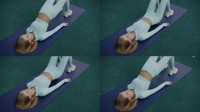 穿着蓝色运动服的运动女性在瑜伽垫上做臀肌桥练习