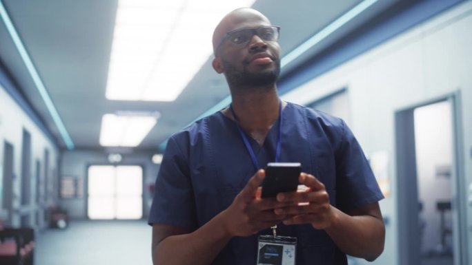 男性护理护士使用智能手机进行日常医院操作和沟通。黑人青年诊所专业人员在现代公共卫生机构开展网络医疗工