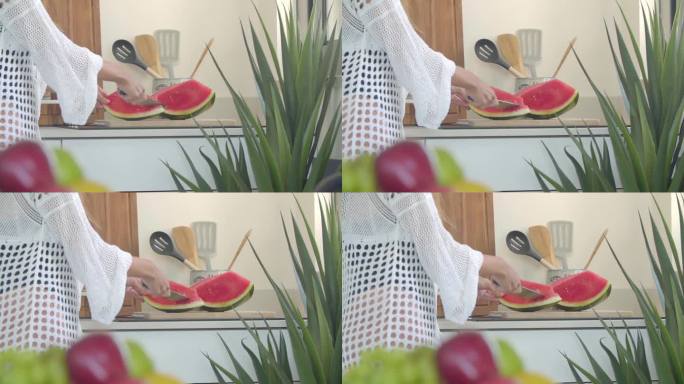 一个女人在厨房用一把大刀切熟西瓜的瓤。缓慢的运动。