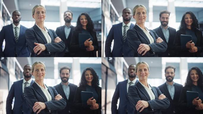 一群才华横溢的年轻商务人士站在现代办公环境中的摆拍。成功的团队在镜头前微笑，由自信的女CEO领导。慢