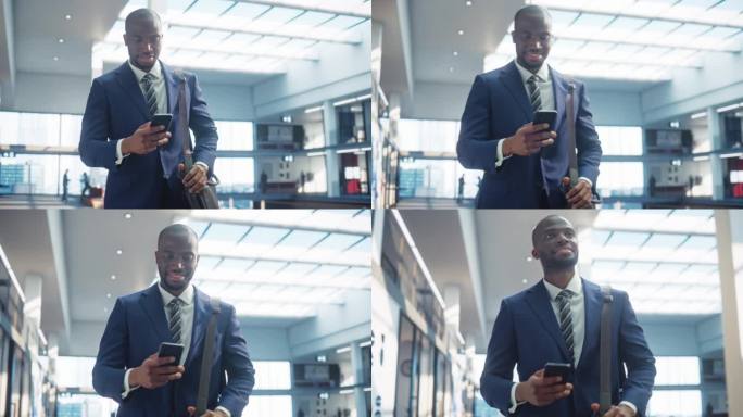 穿着完美剪裁西装的年轻黑人男子的肖像走在公司办公室的走廊上，他微笑着使用智能手机。成功的商人通过短信