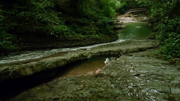 山间涌流。有创造力。河水从高大的绿树上流过，构成了河流，可以看到走路旅行的人。高品质4k画面