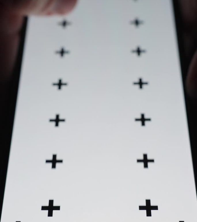 垂直视频。一名男子在黑暗中坐在马桶上滚动智能手机的特写，屏幕布局为白色，带有跟踪标记。
