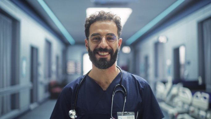一个拉丁医疗保健专业人员对着相机摆姿势，微笑着看着相机的肖像。戴眼镜在医院办公室工作的临床医师或护士