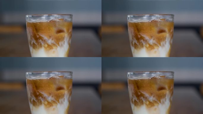 冷咖啡的宏观视角。慢镜头，一个女人往煮好的咖啡里扔冰块。冰块漂浮在咖啡表面。探测器镜头。