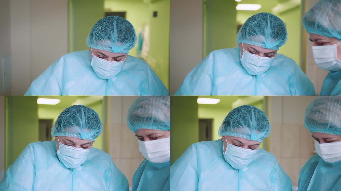 戴口罩的医生。身穿医疗服的女护士的低角度镜头。穿着工作服的医生画像。手术室低角度拍摄，助手在手术中向
