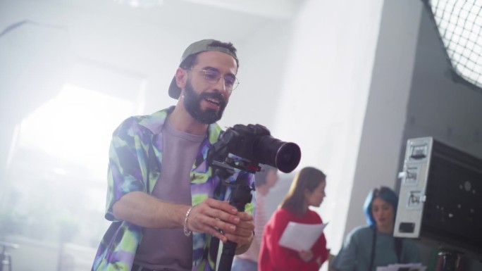 一名男性摄像师在拍摄商业广告时使用稳定器并给模特指示的慢动作肖像。艺术家使用数码相机制作视频作为创意