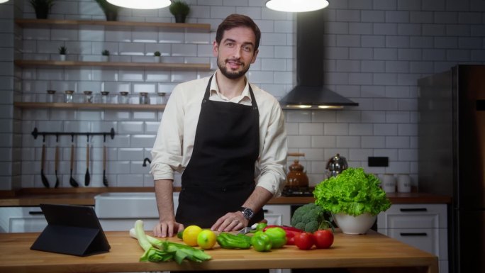 视频博主专业男厨师在围裙录制视频烹饪课关于素食餐在现代厨房