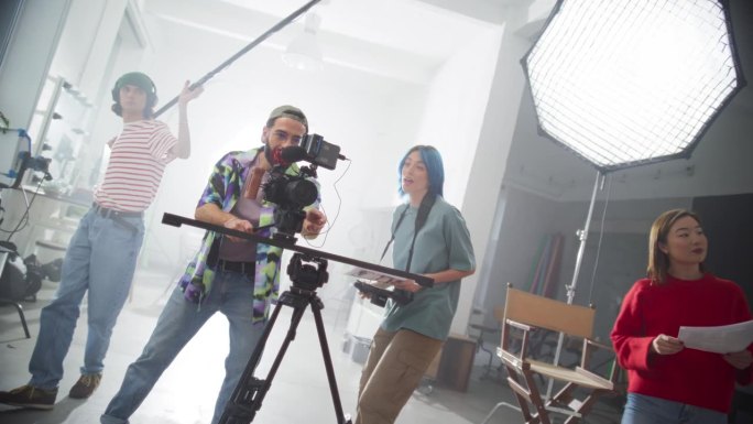 创意团队一起拍摄音乐创意视频的慢动作动态镜头:年轻的电影行业工作者为客户准备视频内容，使用现代技术