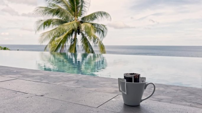 一杯咖啡和一袋煮好的咖啡，早上在游泳池旁边喝一杯咖啡，可以欣赏到令人难以置信的海景和棕榈树，晴朗的天