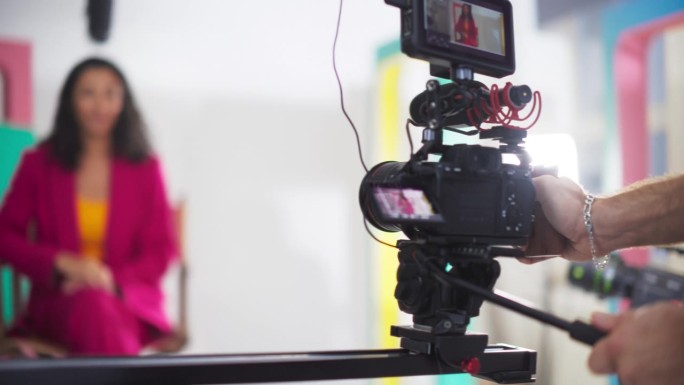 剧组人员和女电视主持人用现代数码相机拍摄电视节目的肖像。内容创作者团队制作教育视频发布到网上。慢动作