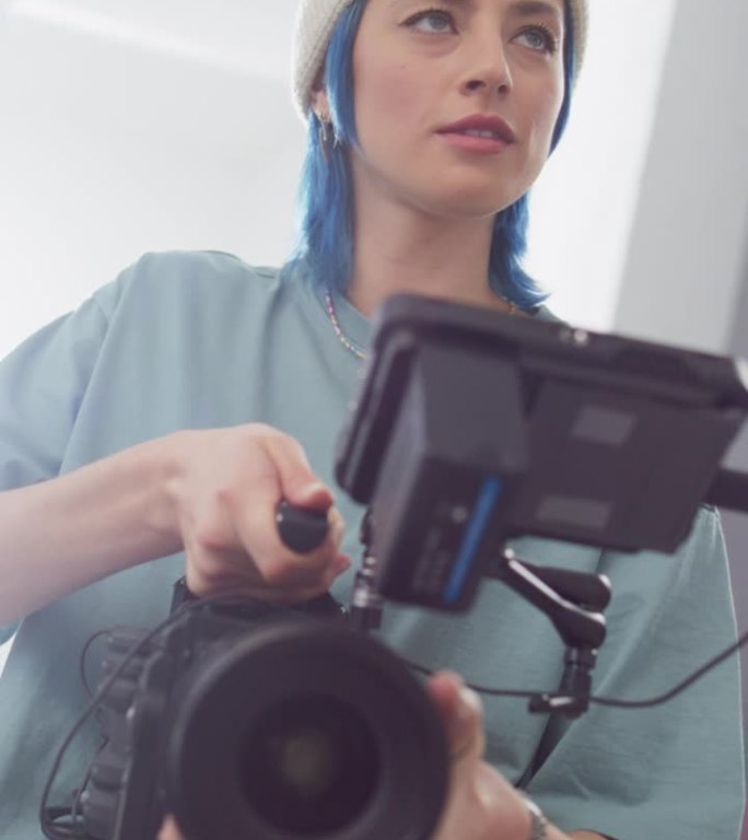 垂直屏幕:慢动作拍摄的女摄影师在拍摄设置，使用数码相机拍摄高质量的镜头为电影项目。操作相机的创意女性