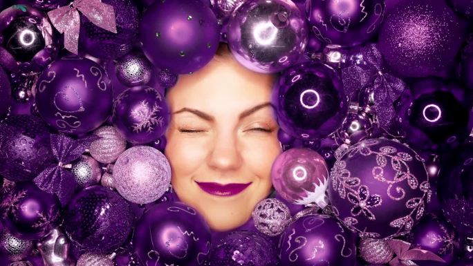 快乐的女人脸上洋溢着紫罗兰色的圣诞树玩具球带来的喜悦。假期