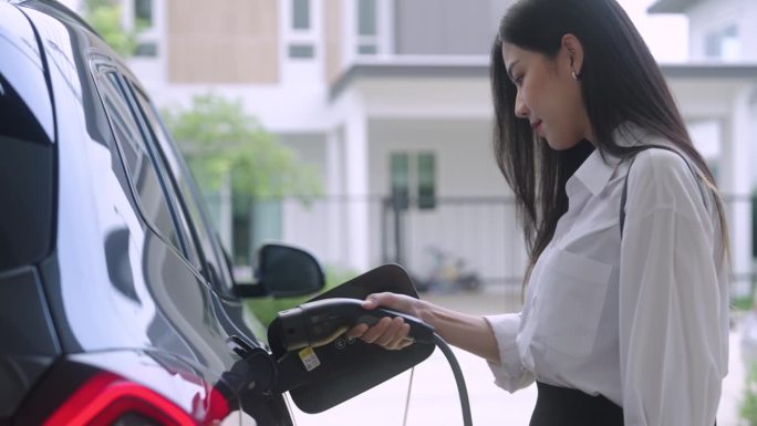 一位女士给她的汽车插上电源充电，并意识到她的能源消耗和碳足迹。