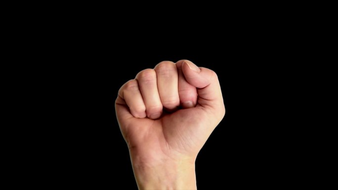 一个男性的手举着一个经典的力量或拳头手势的特写镜头，背景是纯黑色的